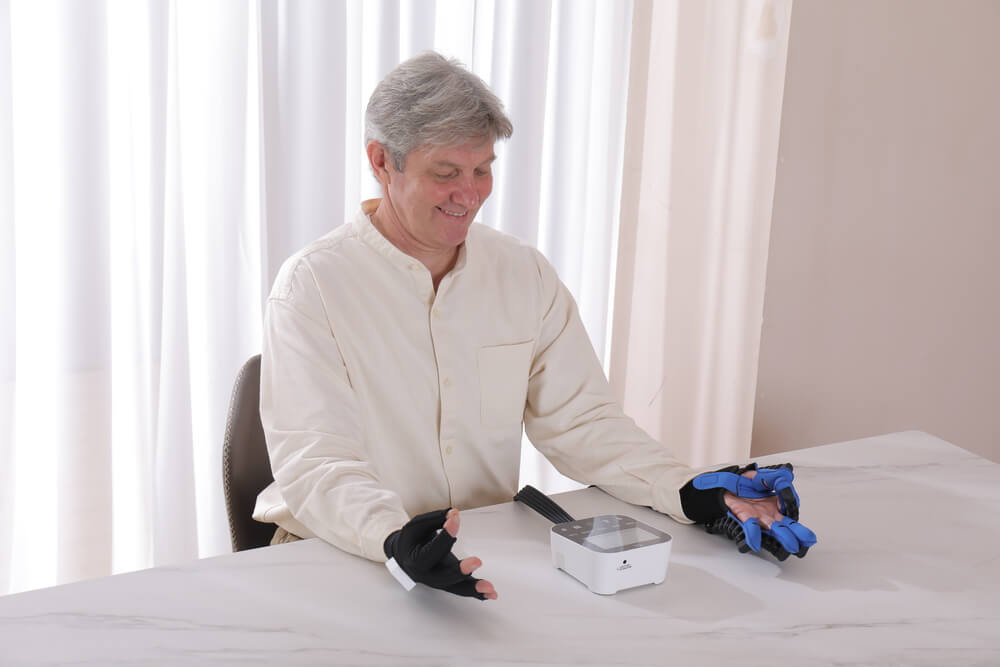 Patient at a table at home looking at the task, wearing the wireless data glove and the power glove