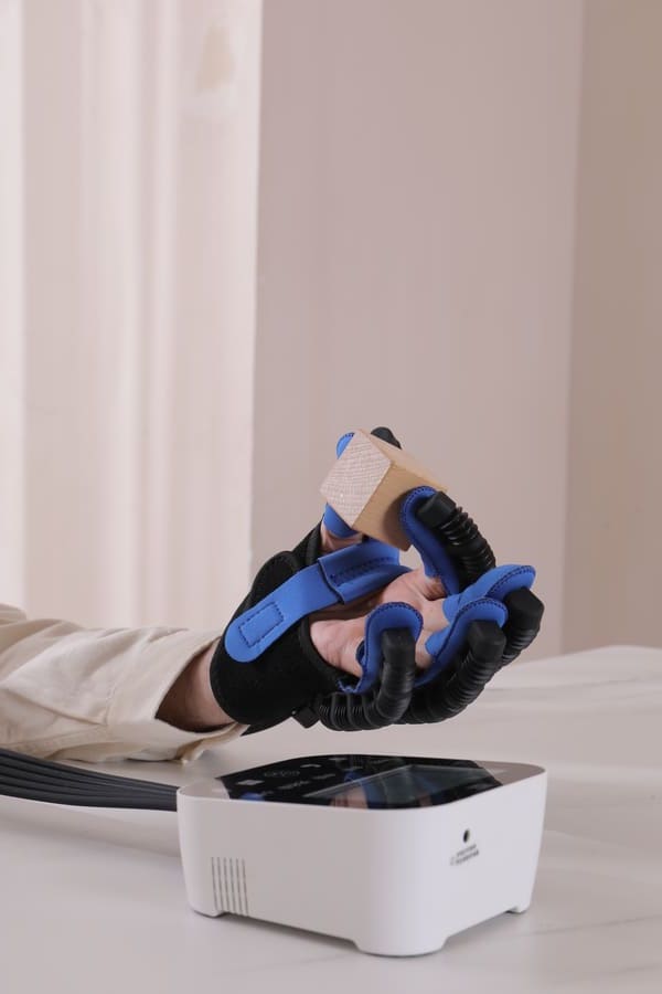Syrebo C12 power glove holding a wooden block above the control unit